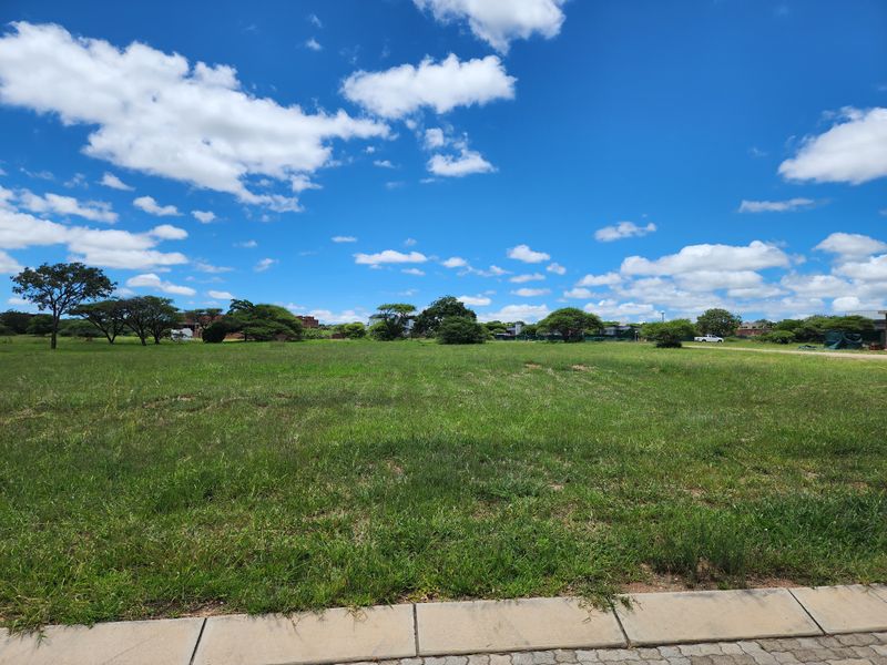 A clear, level residential vacant land plot featuring established grass and mature trees, ready for development.
