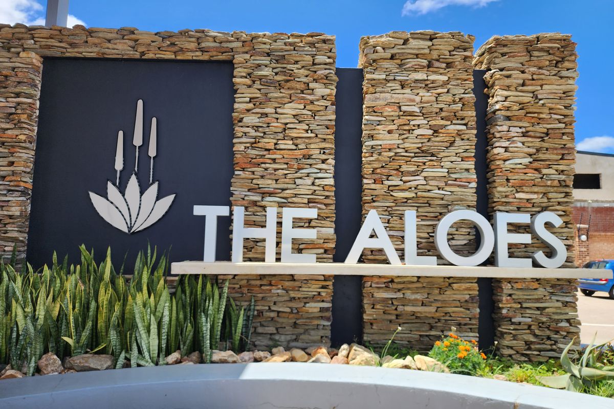 A well-maintained stone-clad entrance signage feature for The Aloes residential estate, showcasing quality masonry and modern branding.