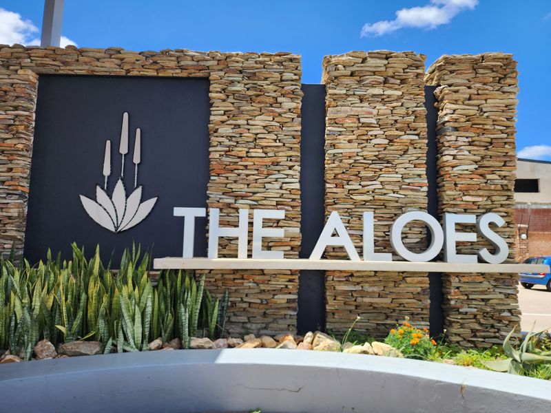 A well-maintained stone-clad entrance signage feature for The Aloes residential estate, showcasing quality masonry and modern branding.
