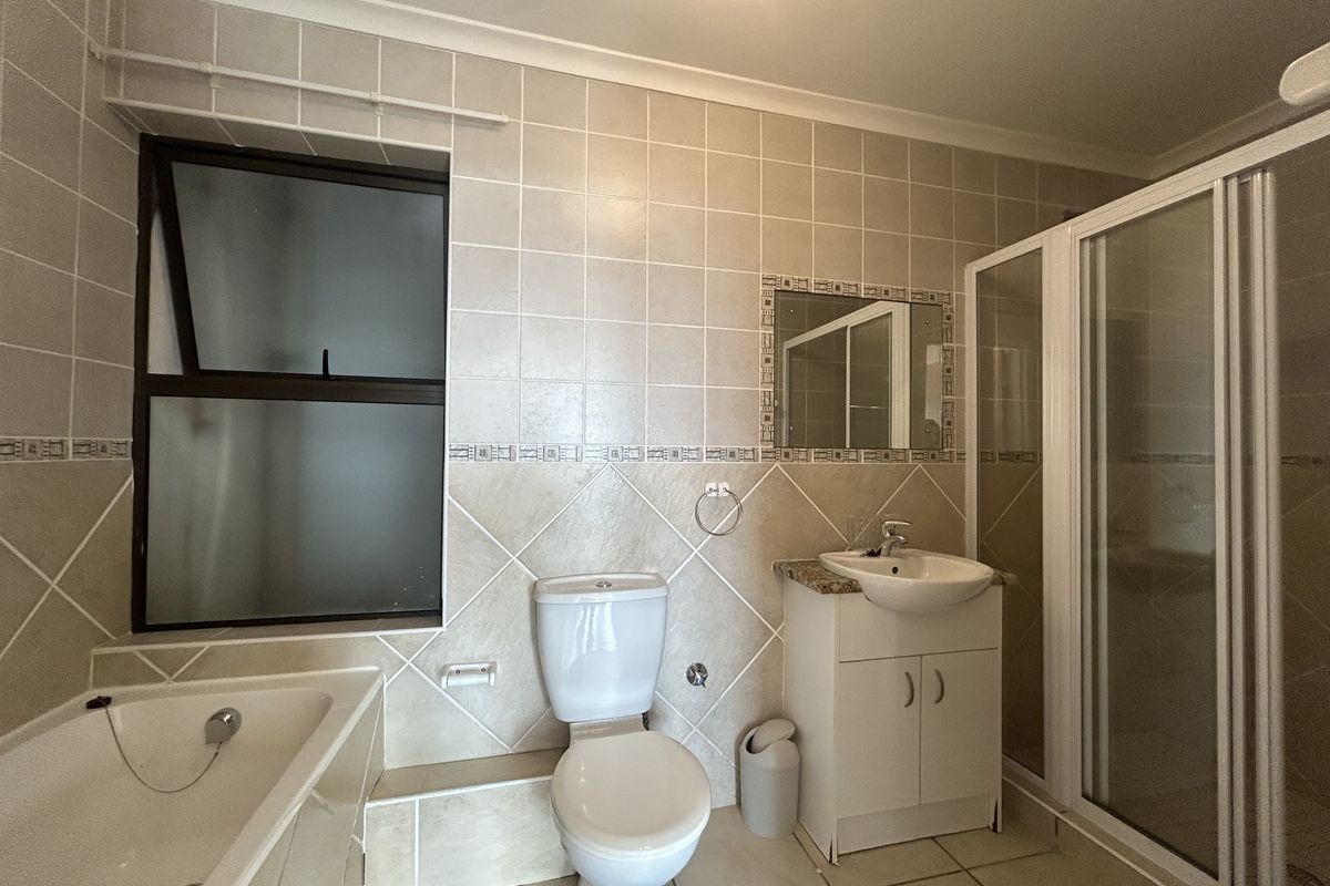 A functional bathroom featuring a built-in bathtub, separate shower enclosure, toilet, and a vanity basin with storage.