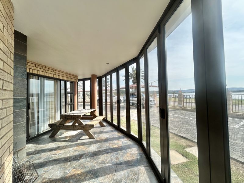 A covered patio area featuring large glass stacker doors, tiled flooring, and brick wall accents, offering a bright and open outdoor living space.
