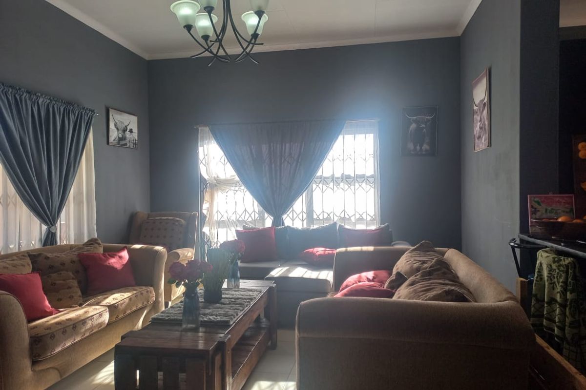 A cozy living room featuring dark grey walls, tiled flooring, and a central chandelier, providing a comfortable space for relaxation.