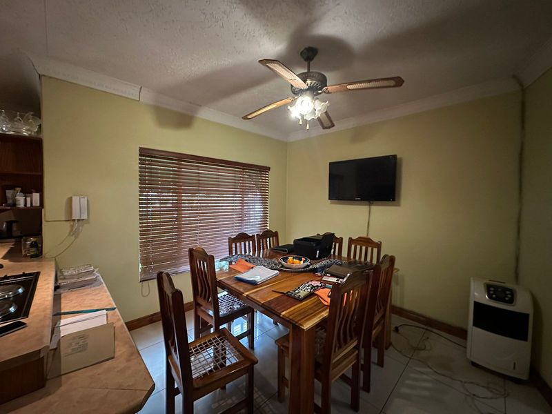 A functional dining area featuring tiled flooring, a ceiling fan, and venetian blinds, providing a practical space for family meals.