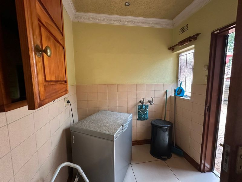 A functional laundry area featuring tiled splashbacks, built-in cabinetry, and direct access to the exterior.
