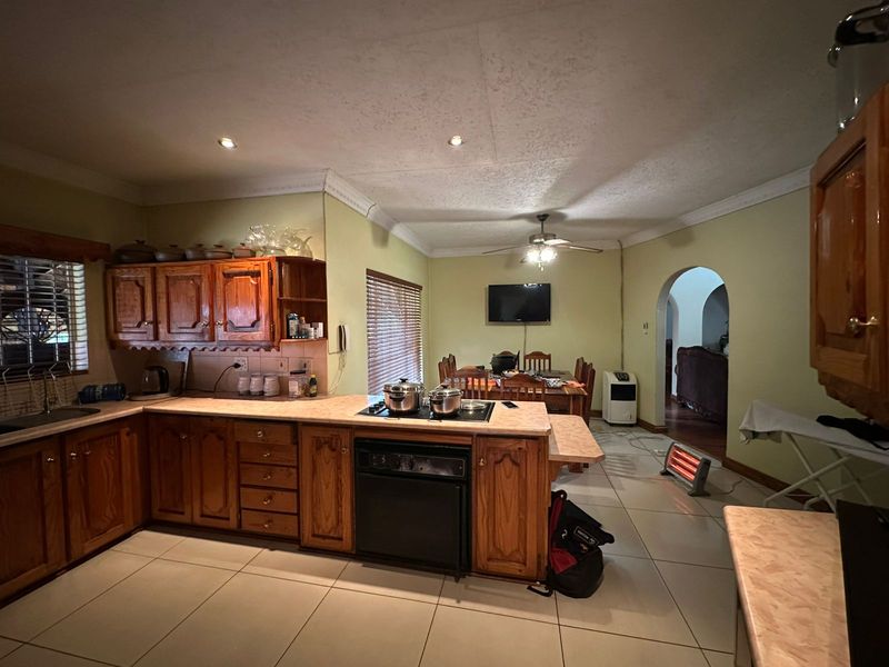 Open plan kitchen and dining area featuring traditional wooden cabinetry, tiled flooring, and an archway leading to adjacent living spaces.