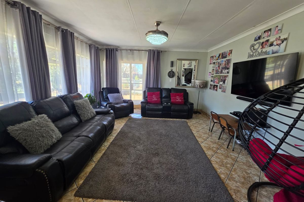 A spacious living room featuring tiled flooring, large windows with natural light, and direct access to the outdoor area.