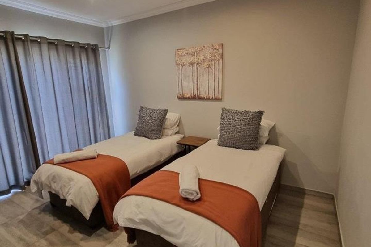 A well-maintained bedroom featuring neutral wall tones, tiled flooring, and recessed downlighting, providing a clean and functional sleeping space.