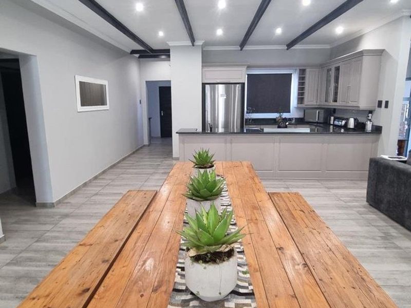 Spacious open-plan living and kitchen area featuring modern cabinetry, granite countertops, tiled flooring, and decorative exposed ceiling beams.