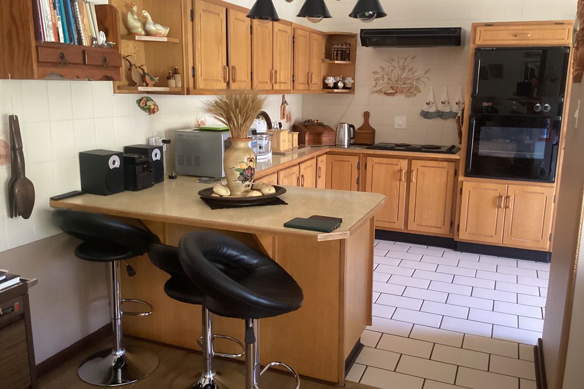 A functional kitchen featuring wooden cabinetry, a breakfast bar, built-in oven, and tiled flooring, offering a classic layout with ample storage space.