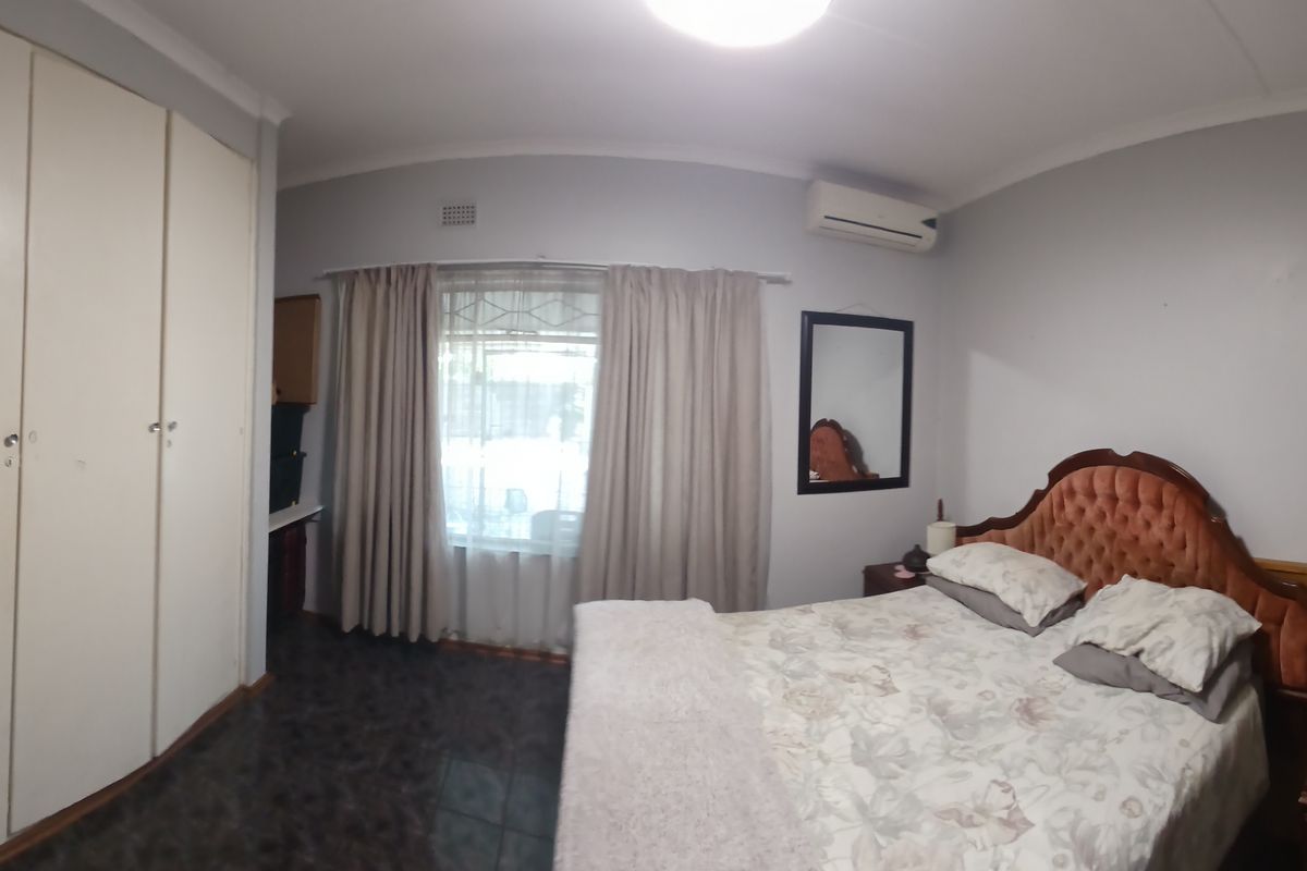 A bedroom featuring built-in cupboards, tiled flooring, and a wall-mounted split-system air conditioner.