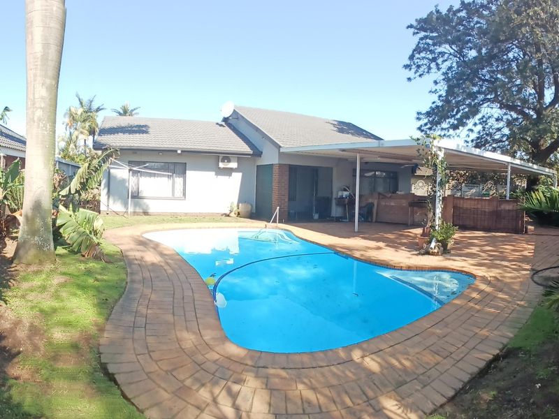 Rear garden area featuring a swimming pool with paved surround and a covered patio attached to the main house structure.