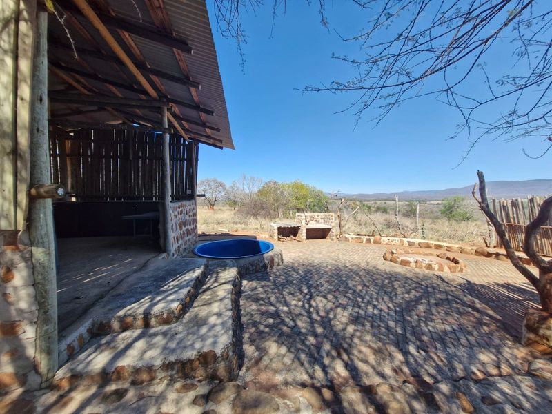 Outdoor entertainment area featuring a covered patio, built-in braai, plunge pool, and paved terrace with expansive rural landscape views.