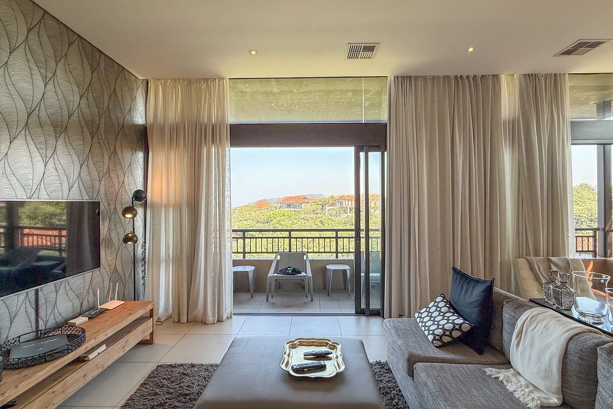 Modern living room featuring large sliding glass doors leading to a private balcony with scenic views and integrated ceiling lighting.