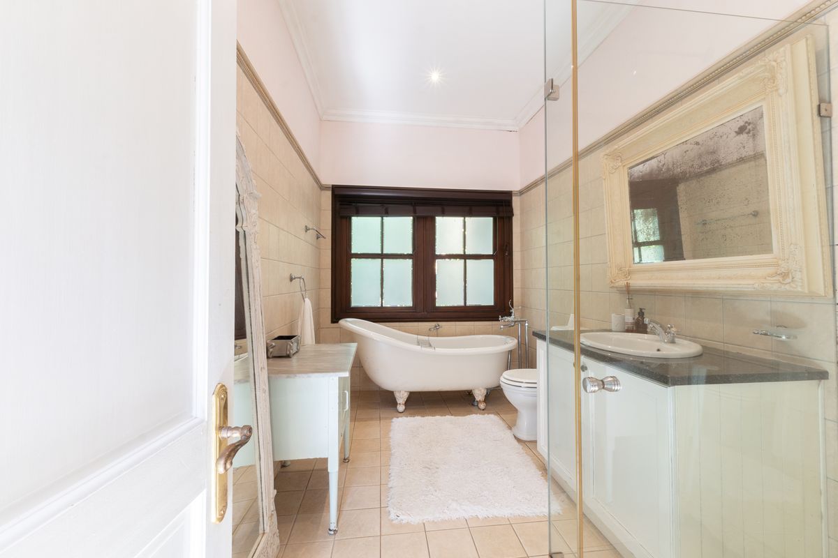 A classic bathroom featuring a freestanding clawfoot bathtub, a vanity with stone countertop, and a separate glass-enclosed shower area.
