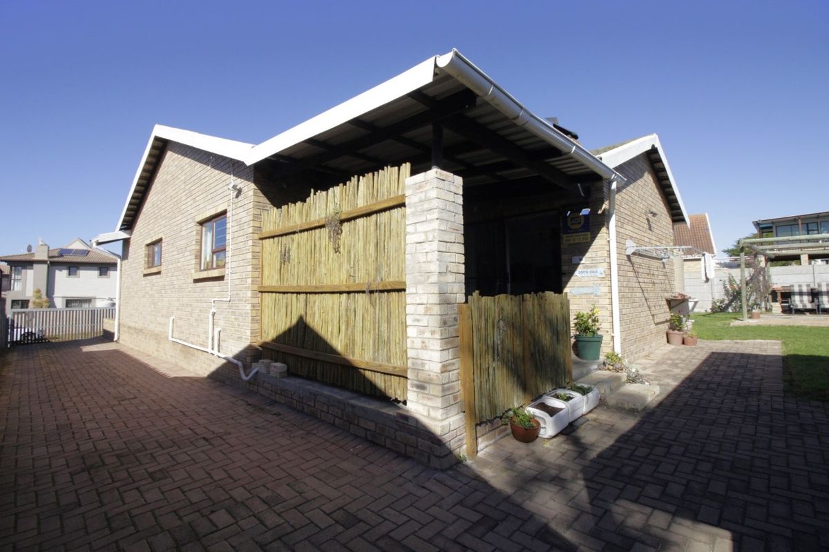 Exterior view of the property featuring a brick facade, covered patio area with timber screening, and paved driveway access.