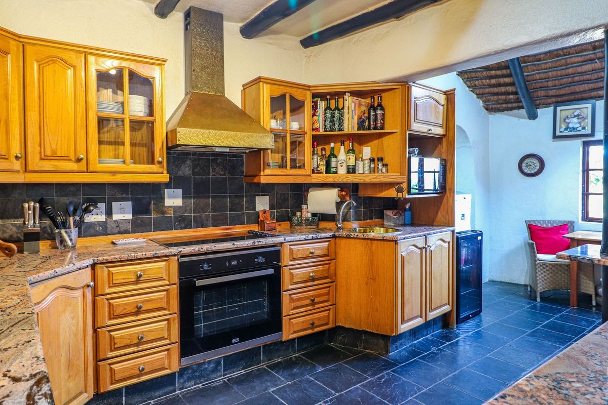 A rustic-style kitchen featuring wooden cabinetry, granite countertops, slate flooring, and exposed ceiling beams, offering a warm and traditional aesthetic.