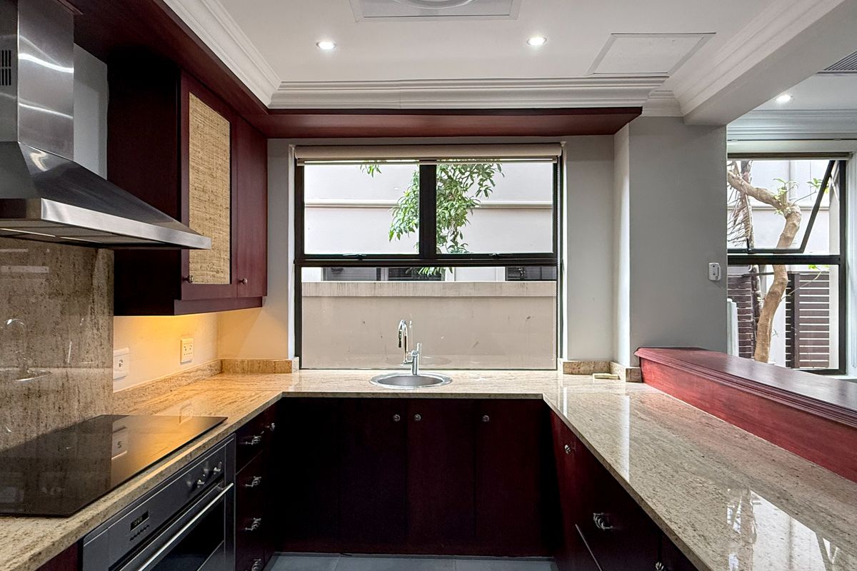 A well-maintained kitchen featuring dark wood cabinetry, granite countertops, a breakfast bar, and integrated stainless steel appliances.