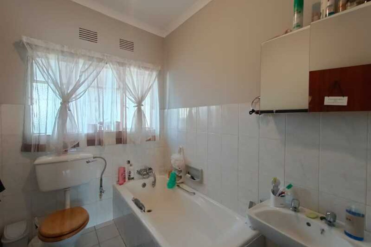 A functional bathroom featuring a standard bathtub, pedestal sink, and toilet with white wall tiling.