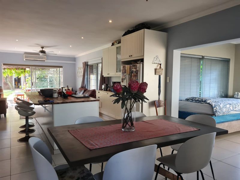 Open-plan living area featuring a kitchen with built-in cabinetry, a central island, and tiled flooring, seamlessly connecting to the dining and living spaces.