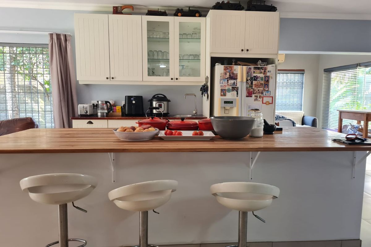 A functional kitchen featuring white cabinetry, a wooden breakfast bar, and tiled flooring, offering a practical layout for daily meal preparation.