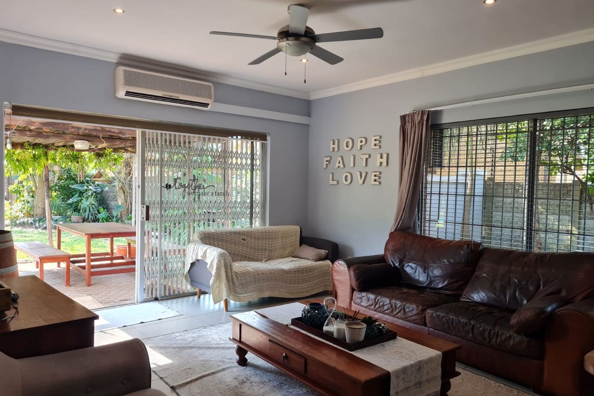 A comfortable living room featuring a ceiling fan, wall-mounted air conditioning unit, and large sliding glass doors providing direct access to the outdoor patio area.