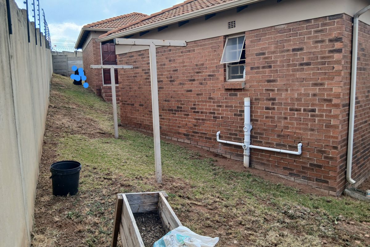 Side exterior view of the property featuring brick facade, exposed plumbing, and a metal washing line structure.