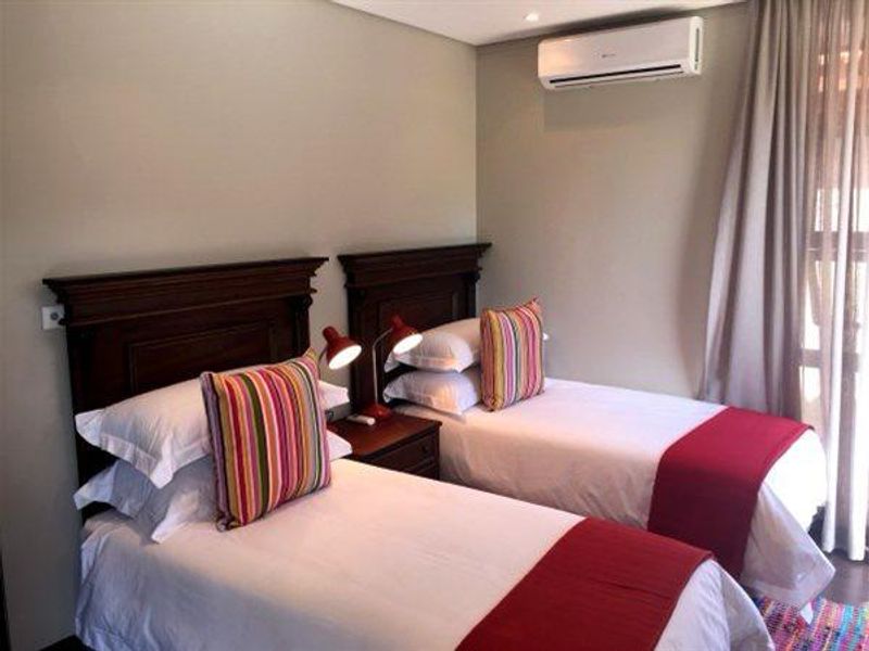 A well-maintained bedroom featuring neutral wall tones, recessed lighting, and a wall-mounted air conditioning unit.