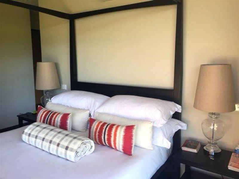 A well-maintained bedroom featuring a dark wood four-poster bed frame and bedside electrical outlets.