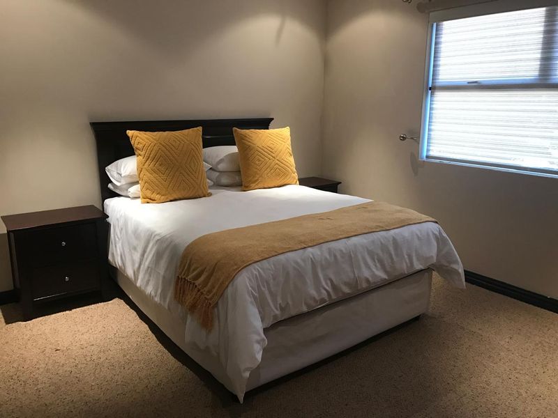 A functional bedroom featuring carpeted flooring and a window with a fitted roller blind.