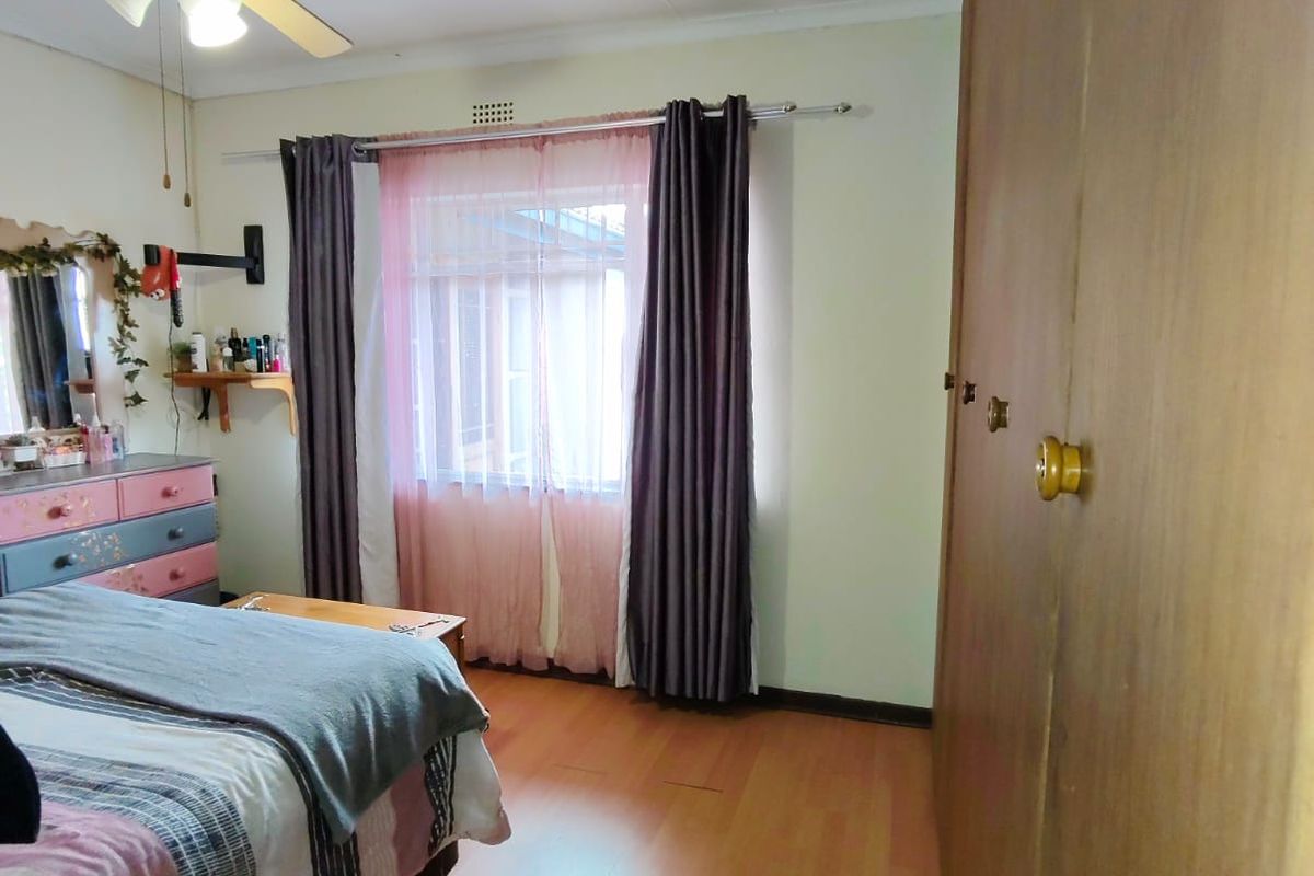 A bedroom featuring built-in wooden cupboards, laminate flooring, and a ceiling fan.
