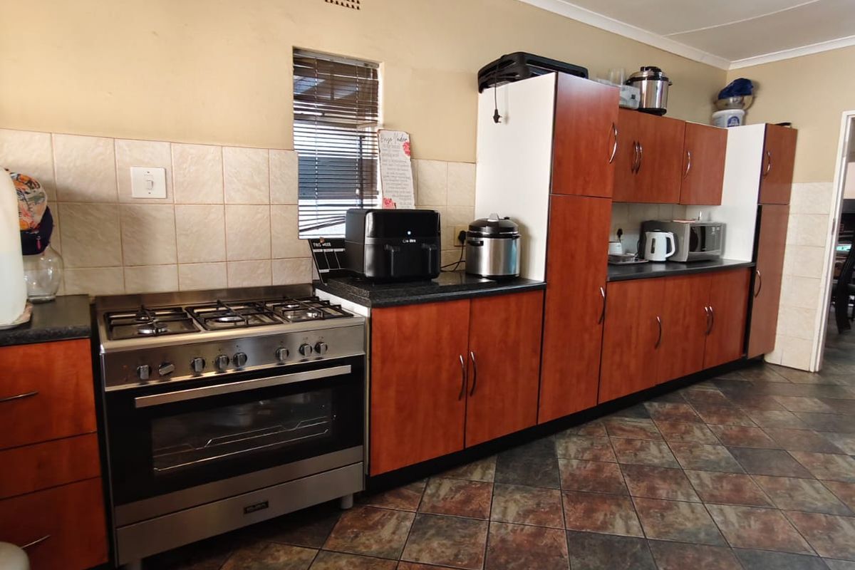A functional kitchen featuring wood-look cabinetry, tiled splashbacks, and a freestanding gas stove with oven, set against a neutral wall finish.