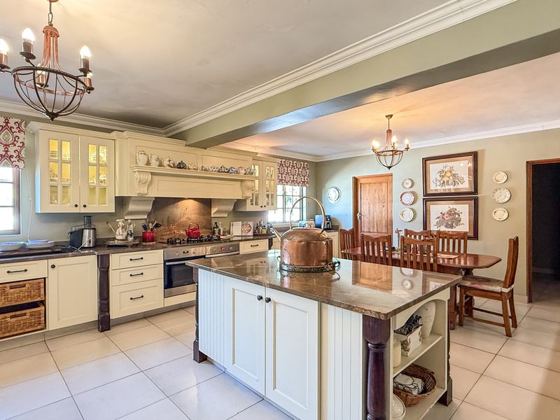 Spacious open-plan kitchen and dining area featuring a central island, granite countertops, built-in appliances, and classic cabinetry with crown molding details.
