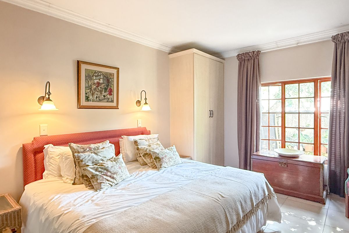 A well-maintained bedroom featuring built-in cabinetry, crown molding, and a large timber-framed window allowing natural light.