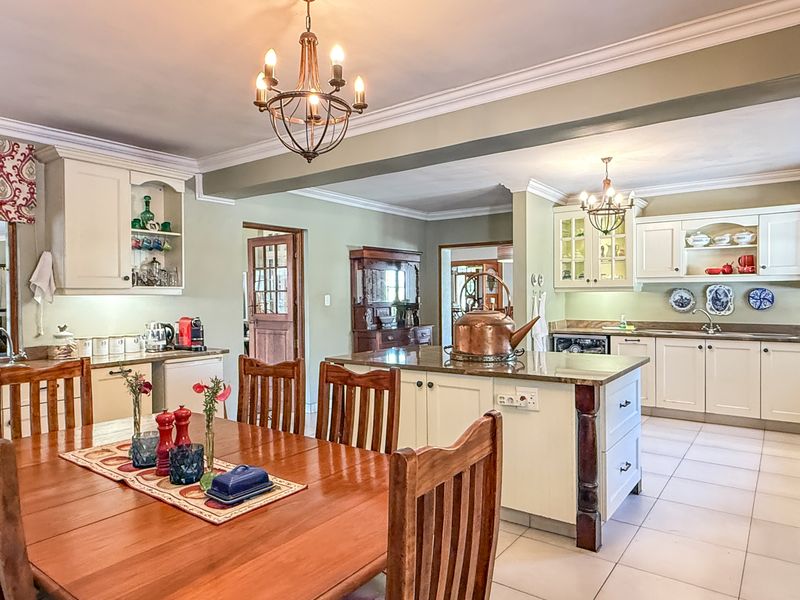 Spacious open-plan kitchen and dining area featuring classic cabinetry, granite countertops, a central island, and elegant chandelier lighting.