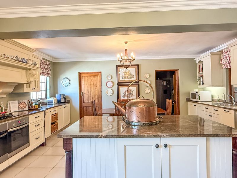 Spacious kitchen featuring a central island with granite countertops, built-in oven, gas hob, and ample cabinetry, offering a functional and classic cooking space.