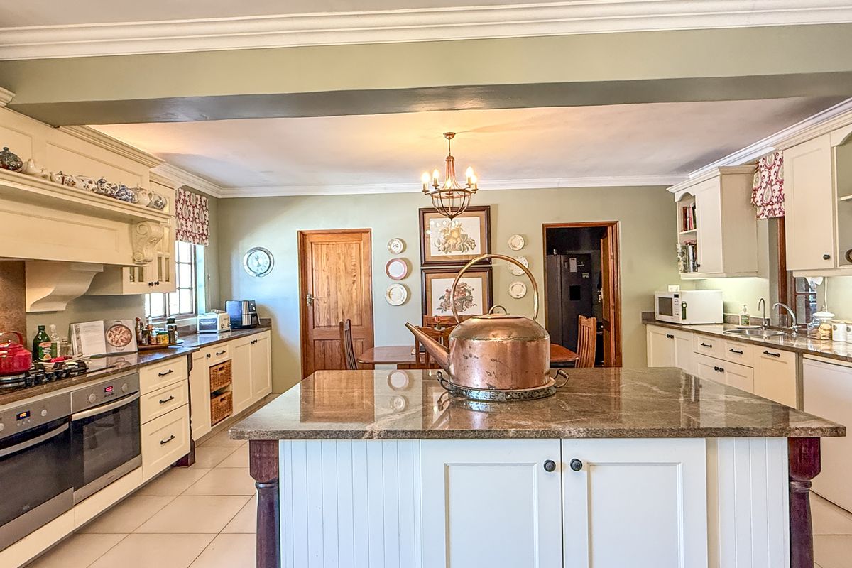 Spacious kitchen featuring a central island with granite countertops, built-in oven, gas hob, and ample cabinetry, offering a functional and classic cooking space.