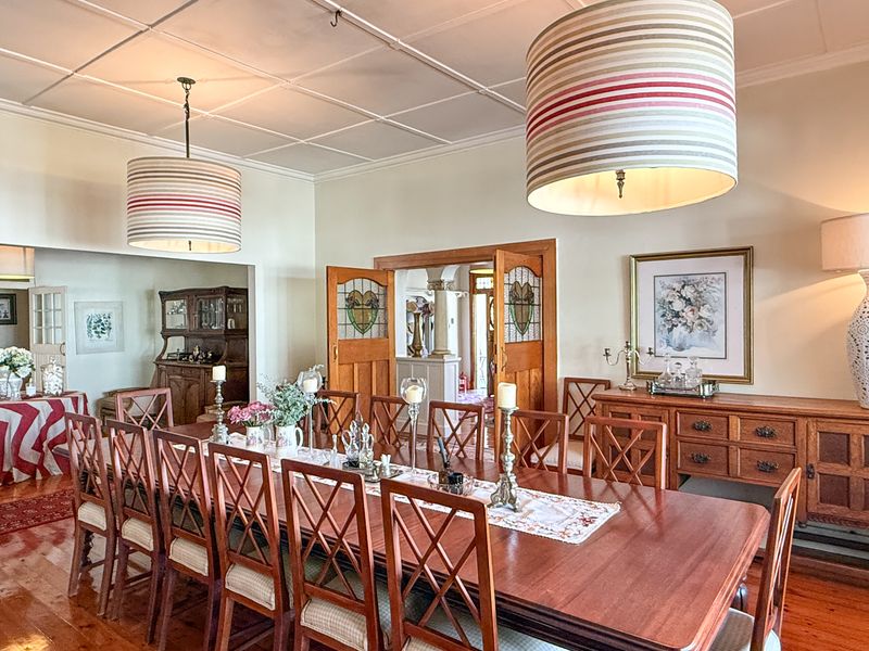 Spacious dining room featuring polished hardwood floors, a coffered ceiling, and elegant stained glass double doors leading to an adjacent living area.