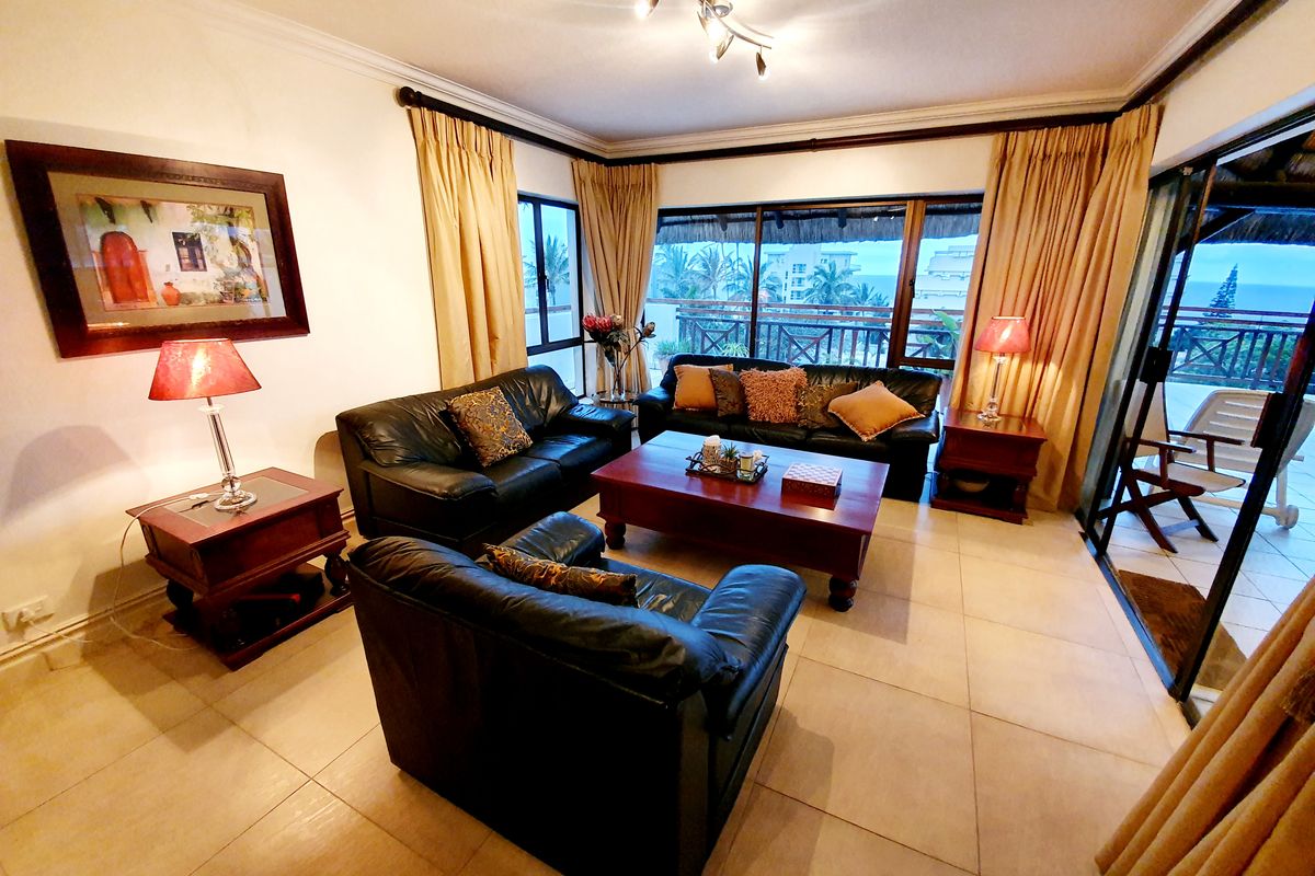 Spacious living room featuring large sliding glass doors that open onto a balcony with scenic coastal views.