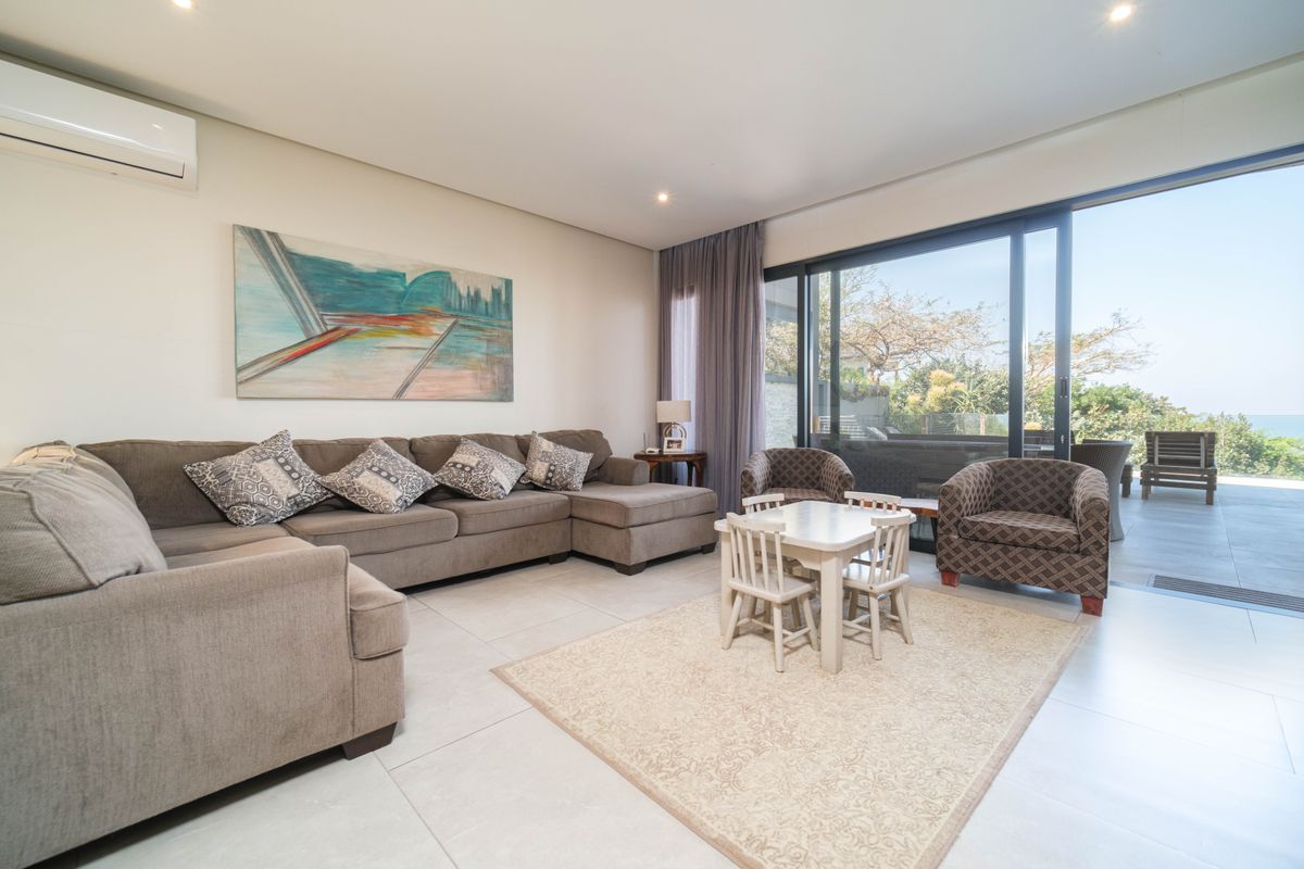 Spacious living area featuring large sliding glass doors that open onto a patio, complemented by recessed lighting and a wall-mounted air conditioning unit.