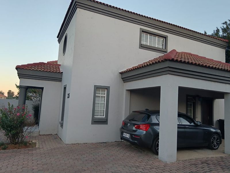 Front elevation of a two-story residential house featuring a paved driveway, covered carport, and neutral exterior paint finish.