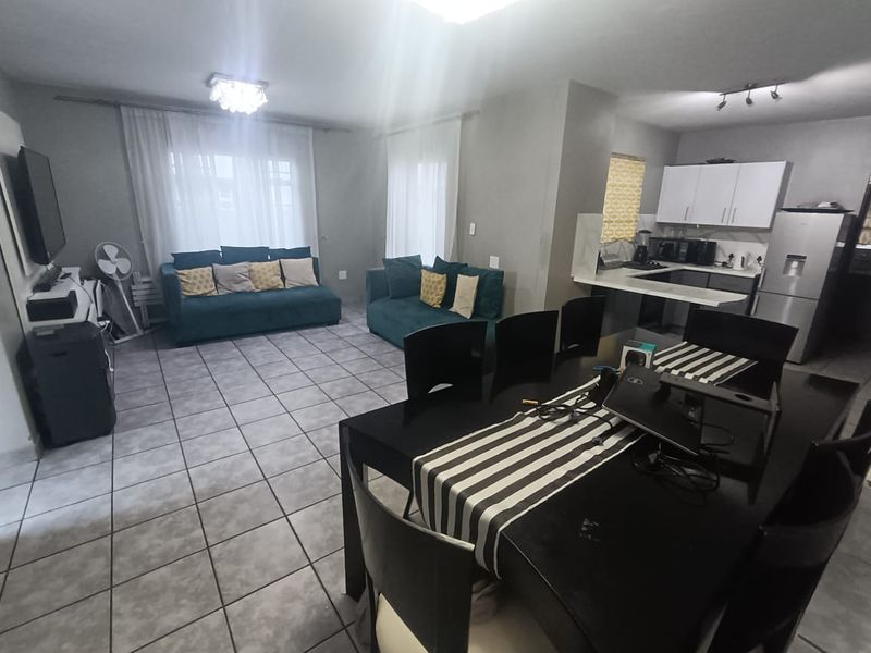Open-plan living and dining area featuring tiled flooring and a functional kitchen with built-in cabinetry and countertops.