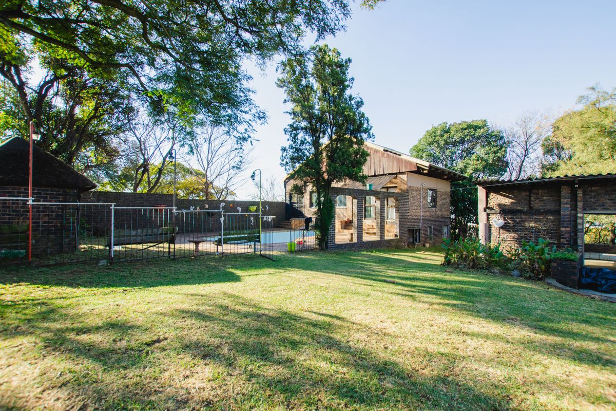 Spacious rear garden featuring a swimming pool, brick boundary walls, and mature trees, providing a private outdoor area for the property.