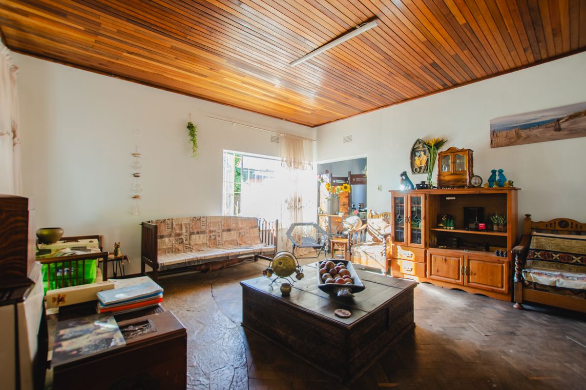 A spacious living room featuring a distinctive timber-paneled ceiling and natural stone flooring, offering a warm and rustic aesthetic.