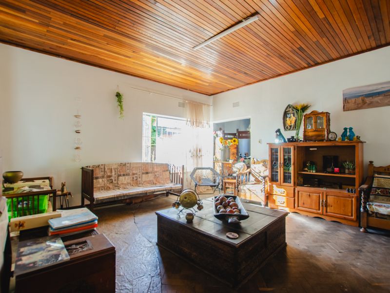 A spacious living room featuring a distinctive timber-paneled ceiling and natural stone flooring, offering a warm and rustic aesthetic.