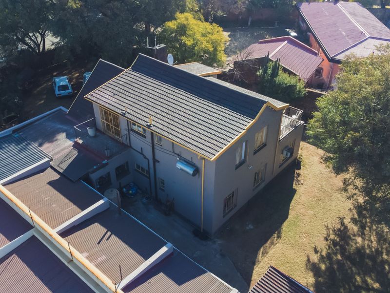 Aerial view of the property showing the multi-level structure, tiled roof, and surrounding garden area.
