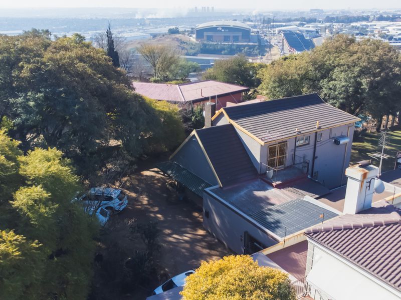 Aerial view of the property showcasing the roof structure, surrounding mature trees, and the expansive neighbourhood landscape.
