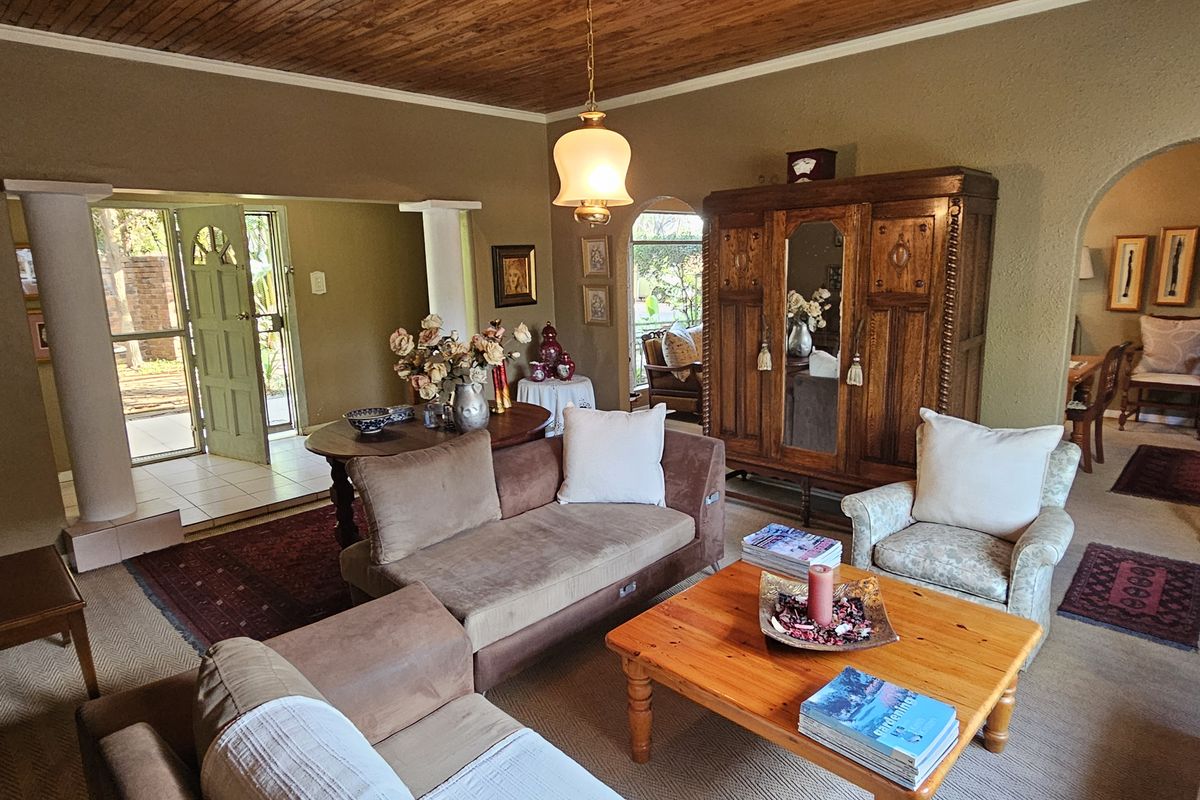 Spacious living room featuring a wood-paneled ceiling, arched entryways, and direct access to the front entrance area.
