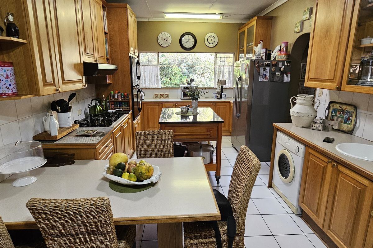 A functional kitchen featuring wooden cabinetry, tiled flooring, a central island, and integrated laundry appliances.