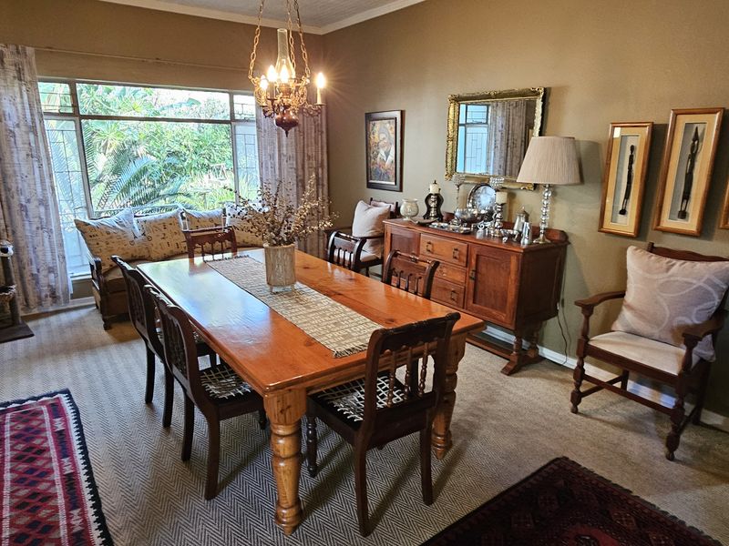 A traditional dining room featuring a large window with garden views, textured wall finishes, and a classic chandelier, providing a warm and inviting atmosphere.