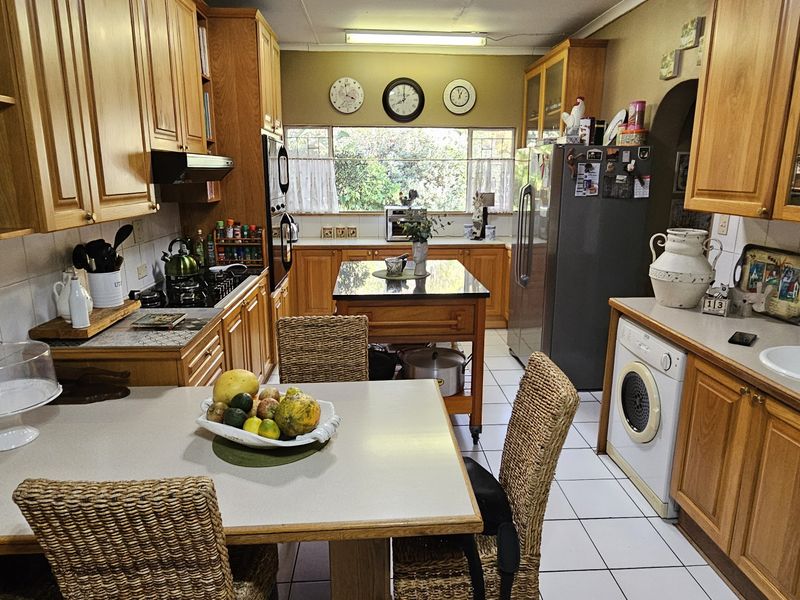 A functional kitchen featuring wooden cabinetry, tiled flooring, a central island, and integrated laundry appliances.